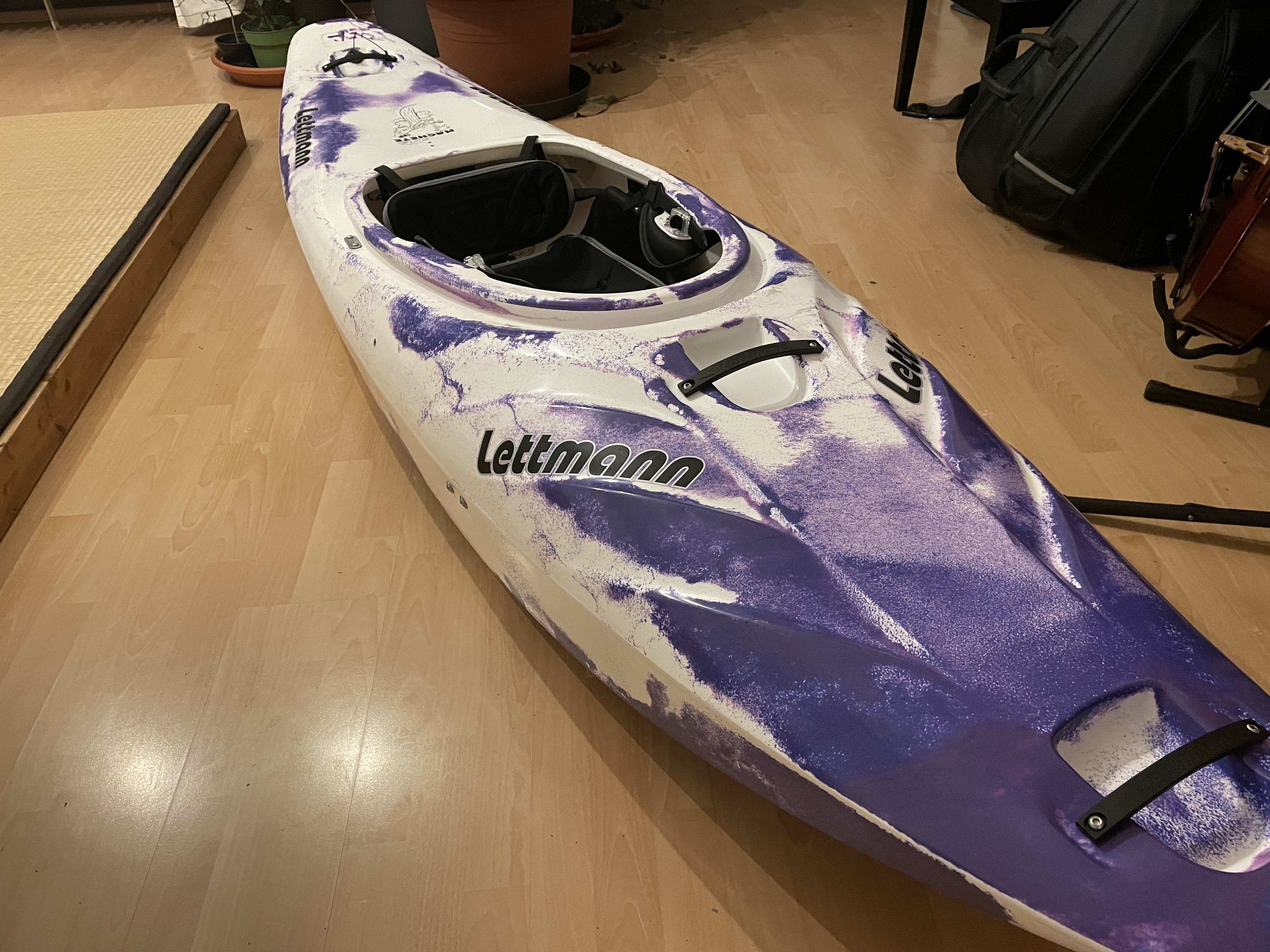 A new whitewater kayak, a Lettmann Machete in purple and white, sitting in our living room