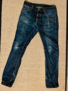A worn pair of blue jeans, with areas at the knees and elsewhere where the colour has worn off