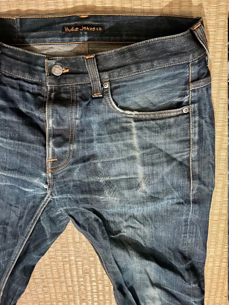 Close-up of the left pocket of a blue jeans. You can clearly see the contours of a smartphone in the coloring of the fabric.