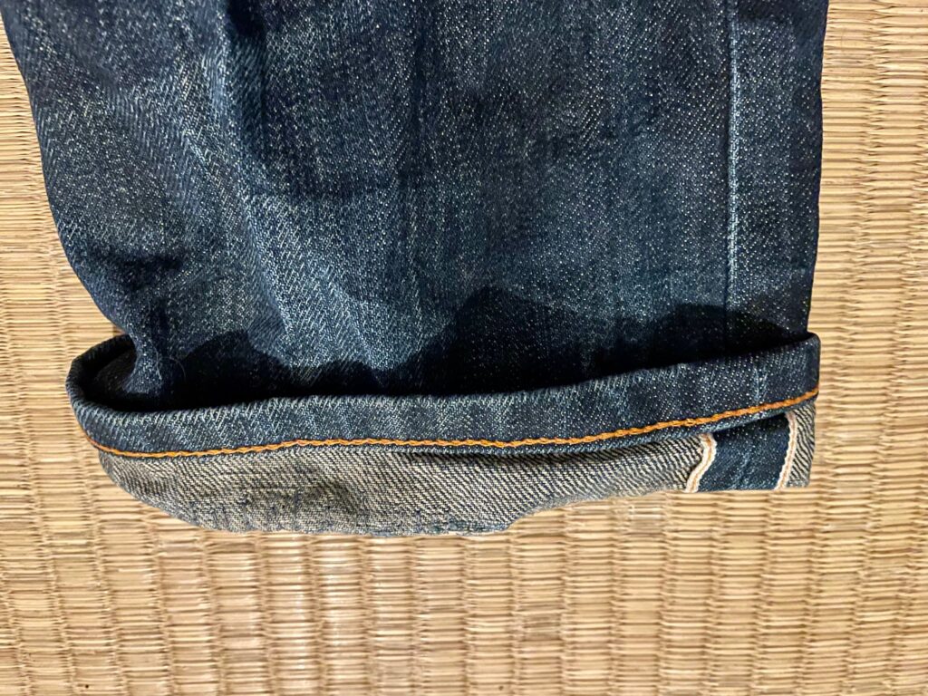 The bottom of a jeans leg. The low end is folded up, and where the fold was worn out, it's been repaired with lots of stitches.
