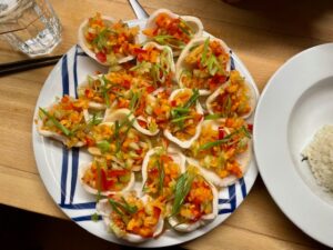 A plate filled with kimchi crunchies: Deep-fried crisps with chopped kimchi on top, decorated with spring onions